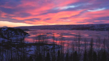 the beautiful colored sky is reflected in the frozen river