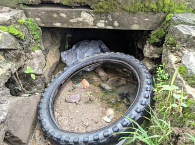 tires in a ditch that is dirty with waste rubbish