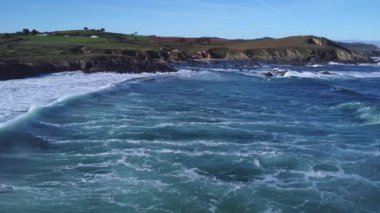 In the video you can see an aerial view where you can see the waves forming foam and curtains of water with rainbows, the cliffs where two men are fishing and meadows of different colors in the background.