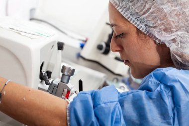 Genç kadın bilim adamı parafin gömülü bir numuneden parçalar elde etmek için döner bir mikrotom üzerinde çalışıyor..