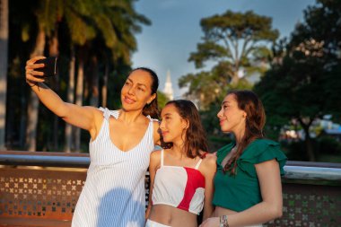 Kolombiya 'nın Cali şehrinde arka planda La Ermita kilisesi olan Cali Nehri Bulvarı' ndaki köprülerden birinde selfie çeken turistler görülüyor. Anne ve kız çocukları seyahat konsepti. Mutlu aile kavramı.