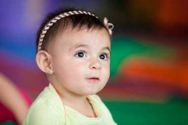 Renkli bir arkaplanda 10 aylık mutlu bir kızın portresi. Bebek konsepti için erken uyarılma.