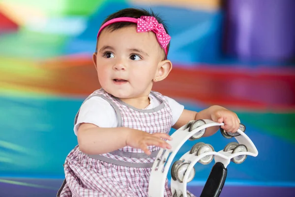 stock image Beautiful ten months baby girl playing with a tambourine. Early stimulation for toddlers concept.