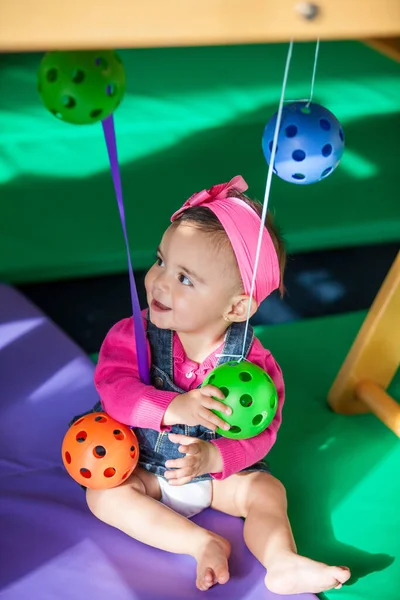 Beautiful ten months baby girl playing with colorful balls. Early stimulation for toddlers concept