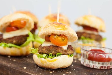 Mini hamburger servis etmeye hazır. Adım adım mini burgerleri hazırlıyorum. Çocuklar ve aperatifler için ev yapımı mini burgerler. Küçük hamburgerler..