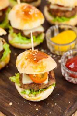 Mini hamburger servis etmeye hazır. Adım adım mini burgerleri hazırlıyorum. Çocuklar ve aperatifler için ev yapımı mini burgerler. Küçük hamburgerler..