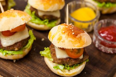 Mini hamburger servis etmeye hazır. Adım adım mini burgerleri hazırlıyorum. Çocuklar ve aperatifler için ev yapımı mini burgerler. Küçük hamburgerler..