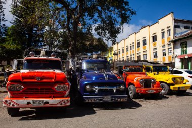 AGUADAS, COLOMBIA - 15 HAZİRAN 2024: Kolombiya 'nın Caldas bölgesinde yer alan tarihi miras kasabası Aguadas' ın merkez meydanındaki renkli geleneksel araçlar.