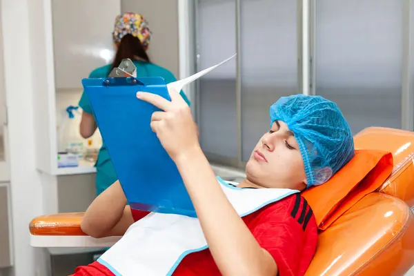 stock image Young male patient reading  an informed consent just before getting a small surgery procedure at the dermatologist office.