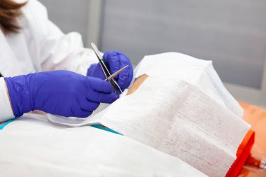 Dermatolog, yaşlı bir hastanın yüzünde deri biyopsisi yapıyor.