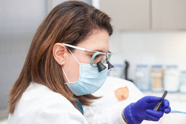 Дерматолог проводит биопсию кожи на лице пожилого пациента