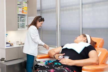Dermatolog, botulinum toksini uygulamak için orta yaşlı bir kadın hasta hazırlıyor. Estetik tıp