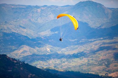 Kolombiya 'daki Antioquia departmanının güzel dağları üzerinde yamaç paraşütü yapan insanlar. Çift paragliding. Ekstrem spor konsepti. 