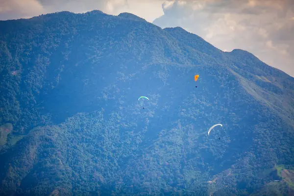 Kolombiya 'daki Antioquia departmanının güzel dağları üzerinde yamaç paraşütü yapan insanlar. Çift paragliding. Ekstrem spor konsepti.