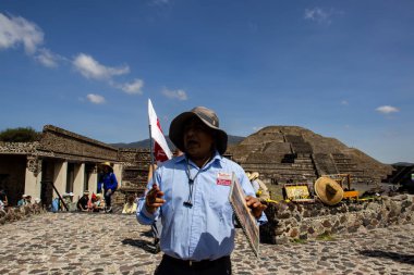 State of Mexico, Mexico - October 24, 2024: Tourist guide at the Teotihuacan archaeological site in a beautiful blue sky day. Pyramid of the Moon. clipart