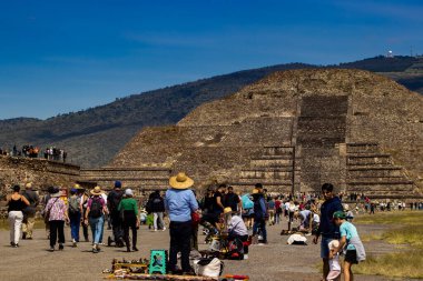 Meksika Eyaleti, Meksika - 24 Ekim 2024: Teotihuacan arkeoloji sahasında güzel bir mavi gökyüzü gününde satıcılar ve turistler. Ölüler Bulvarı ve Ay Piramidi.