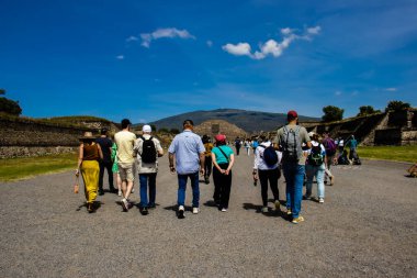 Meksika Eyaleti, Meksika - 24 Ekim 2024: Teotihuacan arkeoloji sahasında güzel mavi bir gökyüzü gününde bir grup turist. Ölüler Bulvarı ve Ay Piramidi.