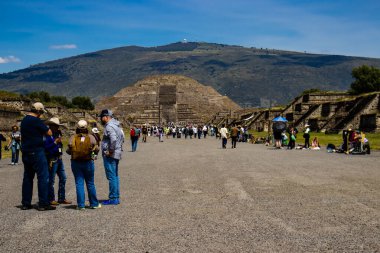 Meksika Eyaleti, Meksika - 24 Ekim 2024: Güzel mavi gökyüzü gününde Teotihuacan arkeoloji sahasında rehberli bir grup turist. Ölüler Bulvarı ve Ay Piramidi.