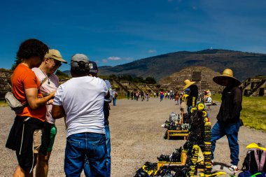 Meksika Eyaleti, Meksika - 24 Ekim 2024: Teotihuacan arkeoloji sahasında güzel mavi gökyüzü gününde turistler ve hediyelik eşya satıcıları. Ölüler Bulvarı ve Ay Piramidi.