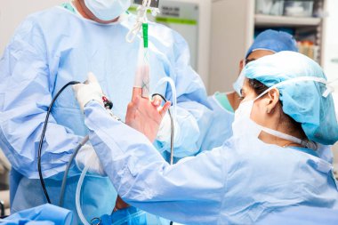 Bir grup ortopedik cerrah bir erkek hastaya bilek artroskopisi yapıyor. Kadın bir doktor ameliyat yapıyor. Ortopedik cerrah. Ameliyat ve sigorta konsepti.