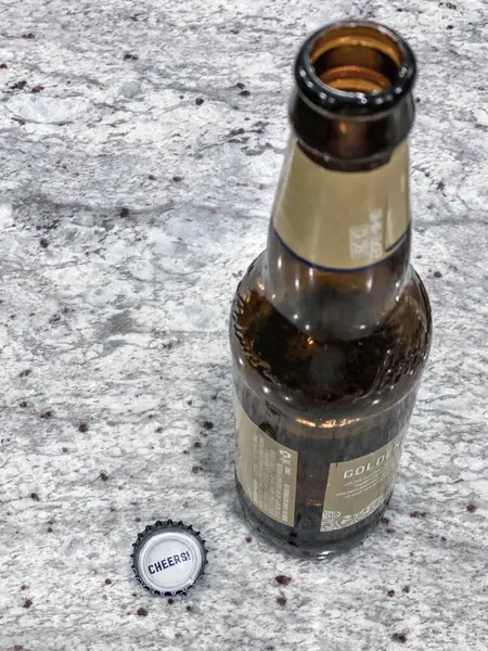 Kapağı açık tek bir kahverengi bira şişesi şapkanın altında neşeli bir karşılama sergiliyor.