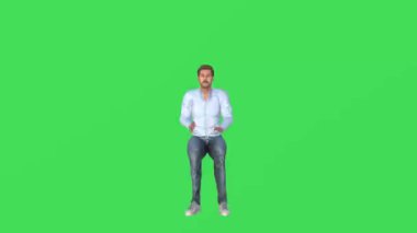 3D yakışıklı genç adam yeşil ekranda oturuyor ve birini arıyor ve izole edilmiş arka plan krom yüksek kalite 4K soruyor.