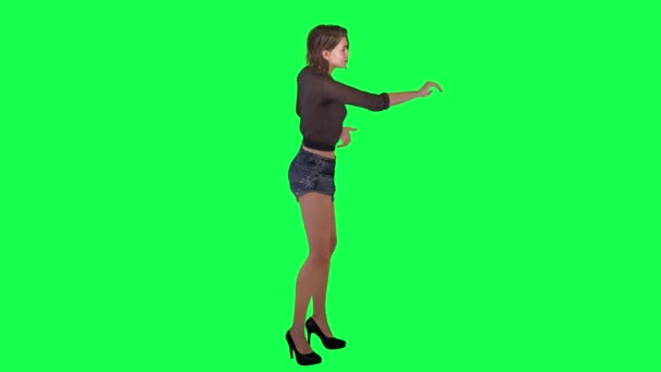 穿着棕色衣服 黑色短裤和高跟鞋的年轻女性旅行者在绿色屏幕上从左角采摘水果 — 图库视频影像