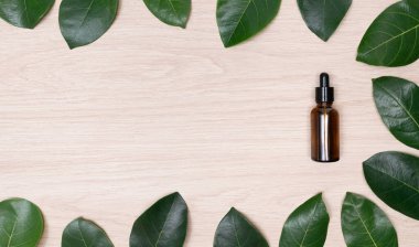 top view glass bottle dropper oil serum with copy space flat lay green leaves on wood background.concept idea for cosmetic  beauty care,medicine,makeup skin nutural product.