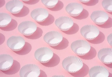 Düz ışığı kapat, boş beyaz kağıt yuvarlak kap kek kapları tatlı pembe minimal arkaplan üzerinde. Tatlı arkaplanı için fikir, fırın malzemesi, duvar kağıdı..