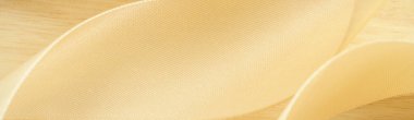 Makro antika altın rengi ipek kumaş kurdeleyi ahşap dokuya yakın tut düz dalga eğrisi soyut arkaplan boş alan. Lüks duvar kağıdı konsepti, zarif web sitesi kapak kapağı arkaplan tasarımı.