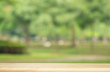 yumuşak ışık yeşil ağaç bahçesi ve bej ahşap masa üst kat bulanık bokeh doğal bahar park arka planı boş fotokopi alanı ile. Organik sağlıklı ürün tanıtım tasarımı.