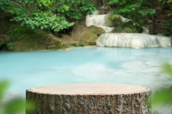 Açık hava şelalesi yeşil tropikal orman arka planında ahşap masa üstü zemin. Doğal su ürünü sunar kaide tezgahı, bahar yaz ormanı cenneti konsepti..