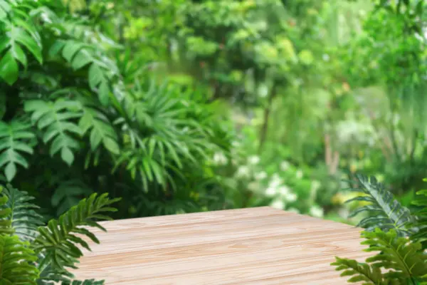 Açık hava tropikal bahçe ormanlarındaki ahşap masa zemininde bulanık yeşil yaprak bitkisi arka planı. Doğal ürün yerleştirme tezgahı sergisi, orman cenneti konsepti..