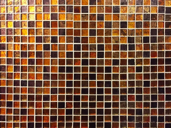 Mosaic of small square tiles in brown and amber colors. It can be used as an interesting beautiful background, texture and in the interior.