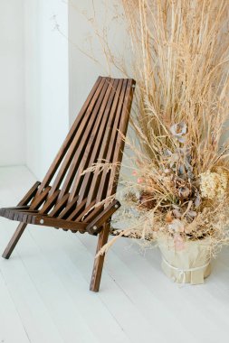 Tarafsız oturma odası konsepti, tasarım ahşap koltuğu, vazoda kurutulmuş çiçekler, dekorasyon ve zarif kişisel aksesuarlar. Şablon. Uzayı kopyala Yüksek kalite fotoğraf