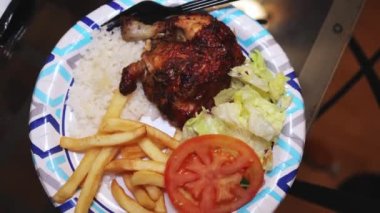 Bir tabak kızarmış tavuk, patates kızartması, lahana salatası, domates ve pilav.