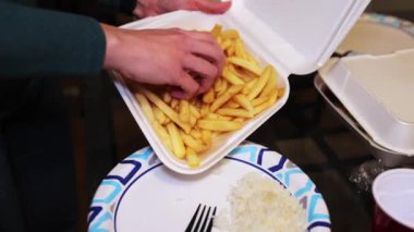 Serving French fries to a large plate with rice to eat with rotisserie chicken