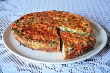 Beyaz masa örtülü bir tabakta yumurta, et, peynir ve sebzeden yapılmış İtalyan omleti. Taze, lezzetli ve sağlıklı bir ev yemeği..