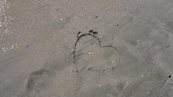 Coração Desenhado Areia Está Sendo Lavado Pelas Ondas Dia Ensolarado — Vídeo de Stock