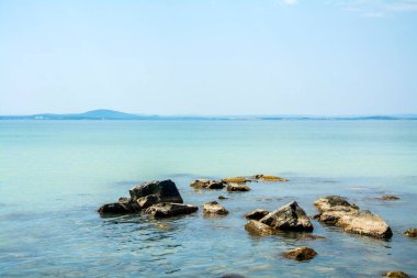 Yazın güneşli bir günde Bulgaristan 'ın Sarafovo kenti yakınlarındaki bir sahildeki sakin sığ sularda kayalar var. Yatay resim