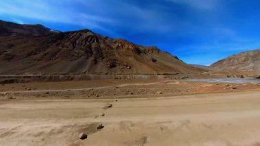 Rocky Dağları 'nın İçinden Bir Yolculuk Bir Tozlu Yol' dan Geçerek Engebeli arazide Dönen Yol, Kayalık Uçurumlar ve Kurak Manzara ile çevrili. Güneş ışığı tozlu havadan süzülerek sıcak ve puslu bir atmosfer yaratır..