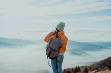 Cheering woman backpacker enjoy the view on sunrise mountain top cliff edgeCheering woman backpacker enjoy the view on sunrise mountain top cliff edge