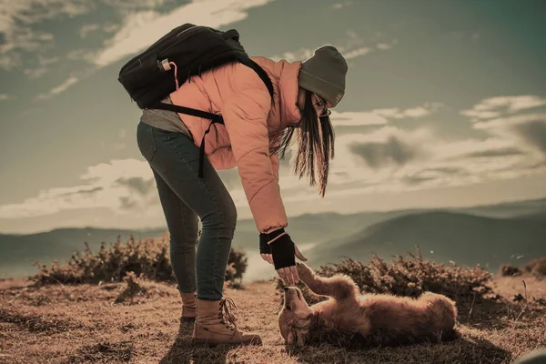 Girl with a dog play in the mountains. Autumn mood. Traveling with a pet.Woman and her dog posing outdoor.