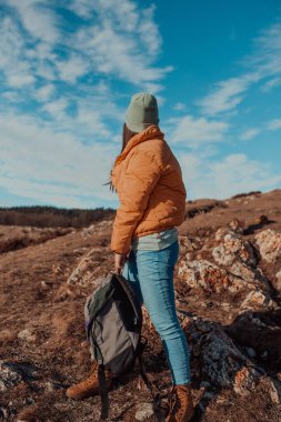 Cheering woman backpacker enjoy the view on sunrise mountain top cliff edgeCheering woman backpacker enjoy the view on sunrise mountain top cliff edge