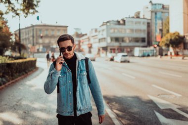 Modern man in sunglasses talking on the smartphone on the street. 
