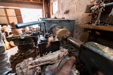 A senior man procesing wood on a lathe and making wooden dishes in the workshop. 