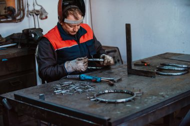 A worker in an industry preparing iron structures for welding. 