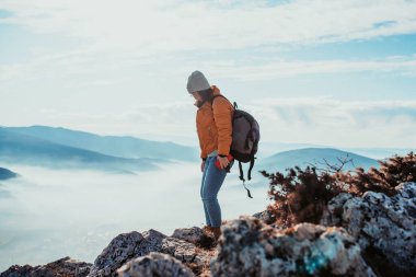 a hiking girl with a backpack on her back watches the morning from the top of the mountain
