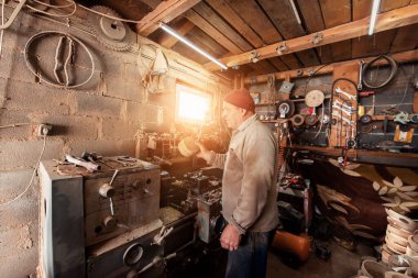 A senior man processing wooden dishes in the workshop in the traditional manual way. 