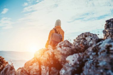 a hiking girl with a backpack on her back watches the morning from the top of the mountain